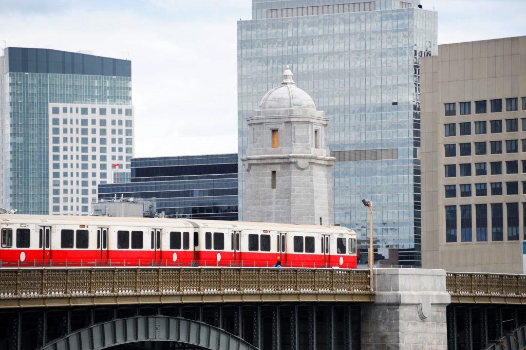 red train crossing long field bridge above Charles river in Boston The 7 Best Boston Suburbs
